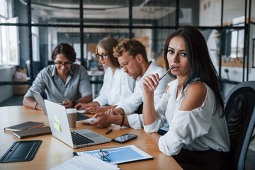 Fototapeta premium Brunette woman in front of employees. Young business people in formal clothes working in the office