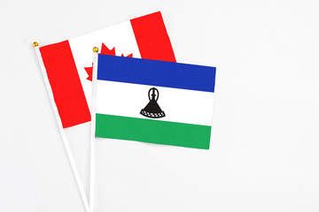 Lesotho and Canada stick flags on white background. High quality fabric, miniature national flag....