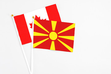 Macedonia and Canada stick flags on white background. High quality fabric, miniature national flag. Peaceful global concept.White floor for copy space.