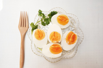 Boiled eggs cut in half, placed in a red bowl, on the tablecloth