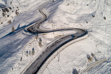 Curved road in the Italian Alps in South Tyrol, during winter / Sunny winter day with harsh shadows and lot of snow