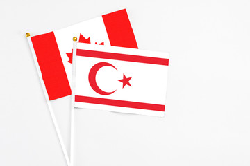Northern Cyprus and Canada stick flags on white background. High quality fabric, miniature national flag. Peaceful global concept.White floor for copy space.