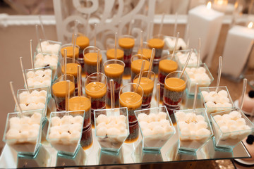 Sweet table. A plates of cakes and muffins with cream. Different fruit desserts in glasses on the table. Restaurant presentation, food, party concept. Luxury table in restaurant.