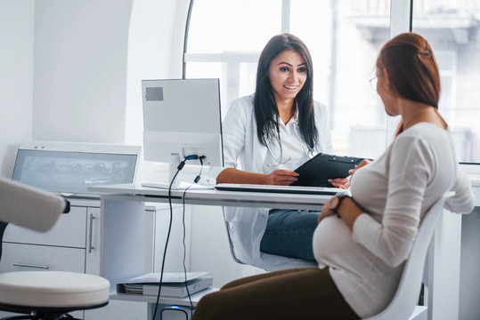 Active conversation. Pregnant woman have consultation with obstetrician indoors