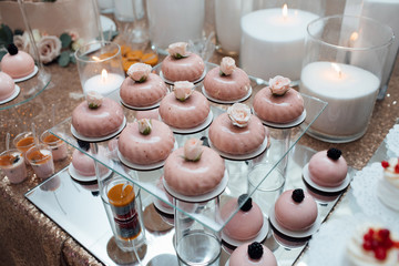 Close up of tray with lot delicious diversity pastry cakes tartlets, beautifully decorated. Candy bar. Dessert table for a party. Wedding reception. Table with desserts and candles. Romantic design.