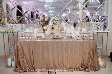 Dessert table for a party. Cake, cupcakes, sweetness and flowers. Table with desserts and candles. Romantic design. Dessert table at wedding reception