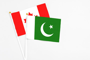 Pakistan and Canada stick flags on white background. High quality fabric, miniature national flag. Peaceful global concept.White floor for copy space.