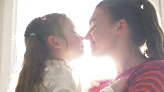Affectionate happy family single mom and cute little child daughter laughing together, foster parent hugging kid girl cuddling touching noses at home
