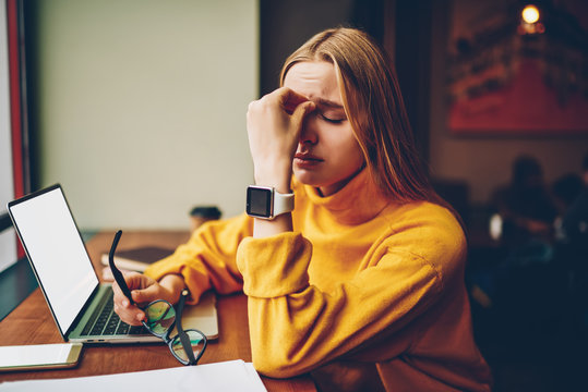 Tired female software developer feeling headache from remote work with laptop computer, exhausted overworked programer sitting at desktop with netbook have problem with wireless 4g connection