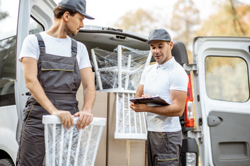 Delivery company employees unloading cargo van vehicle, delivering some goods and furniture to a clients home. Relocation and professional delivery concept