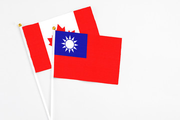 Taiwan and Canada stick flags on white background. High quality fabric, miniature national flag. Peaceful global concept.White floor for copy space.