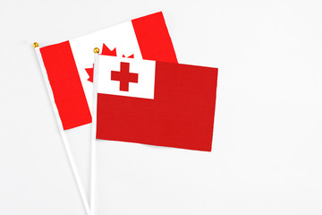 Tonga and Canada stick flags on white background. High quality fabric, miniature national flag. Peaceful global concept.White floor for copy space.