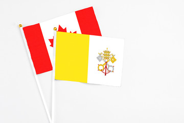 Vatican City and Canada stick flags on white background. High quality fabric, miniature national flag. Peaceful global concept.White floor for copy space.