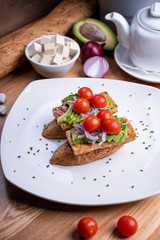 Vegan sandwich with grilled tofu, avocado, cherry tomato, vegetables and scrambled tofu. Chef cooking. Vegan open sandwiche. Healthy food concept.