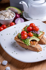 Fototapeta na wymiar Vegan sandwich with grilled tofu, avocado, cherry tomato, vegetables and scrambled tofu. Chef cooking. Vegan open sandwiche. Healthy food concept.