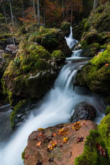 Obraz premium Wasserfall im Herbst mit Moos und bunten Blättern und Felsen
