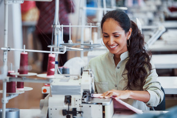 Dressmaker woman sews clothes on sewing machine in factory