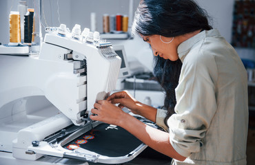 Beautiful female worker is in the sewing factory by the machine