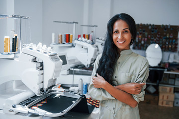 With arms crossed. Beautiful female worker is in the sewing factory