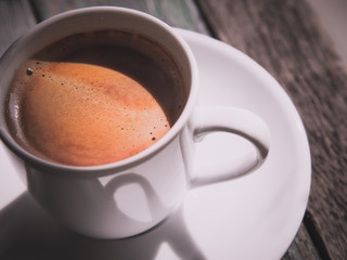 Hot espresso coffee cup on wooden table. Fresh hot Coffee in morning sunlight by top view.