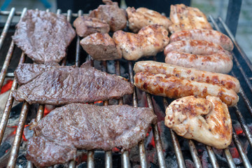Assorted delicious grilled meat and bratwurst  over the coals on a barbecue.