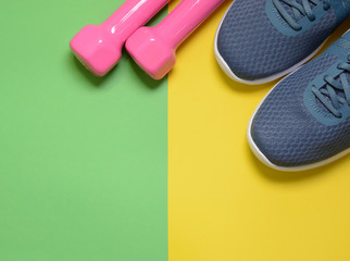 Sport sneakers and dumbbells on yellow green background with copy space for text. Sport objects...