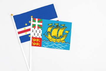 Saint Pierre And Miquelon and Cape Verde stick flags on white background. High quality fabric, miniature national flag. Peaceful global concept.White floor for copy space.