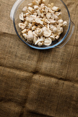 Cut forest champignon mushrooms in glass bowl standing on table covered with sackcloth.