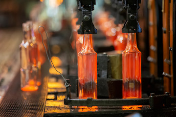 Glassworks. Glass industry. The process of making glass bottles.Molten hot glass containers on...