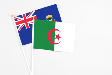 Algeria and Cayman Islands stick flags on white background. High quality fabric, miniature national flag. Peaceful global concept.White floor for copy space.