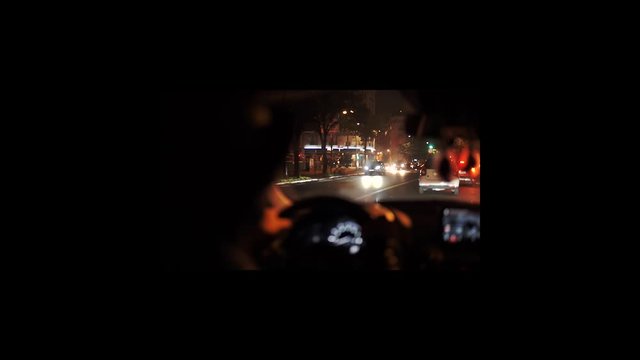Stylish Man in hat driving a Car in Paris at Night, with brurred night street lights