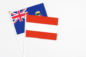 Austria and Cayman Islands stick flags on white background. High quality fabric, miniature national flag. Peaceful global concept.White floor for copy space.