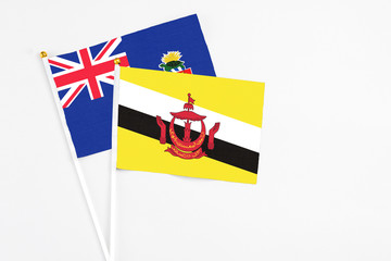 Brunei and Cayman Islands stick flags on white background. High quality fabric, miniature national flag. Peaceful global concept.White floor for copy space.
