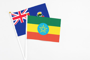 Ethiopia and Cayman Islands stick flags on white background. High quality fabric, miniature national flag. Peaceful global concept.White floor for copy space.