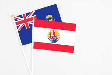 French Polynesia and Cayman Islands stick flags on white background. High quality fabric, miniature national flag. Peaceful global concept.White floor for copy space.