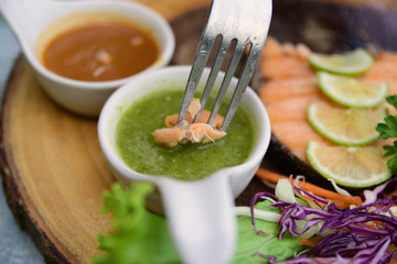 Close up a fork jab a fish soak into chilli sauce, delicious food with thai spicy sauce, grilled...