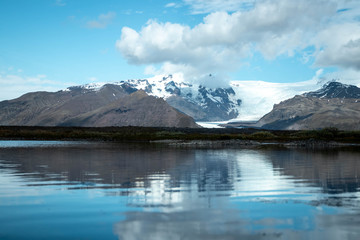 Fototapeta na wymiar View of a glacier in the mountains and reflective lake along the ring road of Iceland's east coast