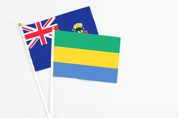 Gabon and Cayman Islands stick flags on white background. High quality fabric, miniature national...