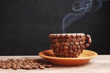 A cup made of coffee beans with smoke standing on a table