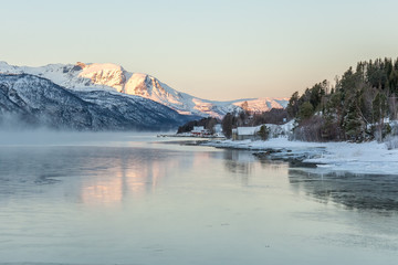Naklejka premium Beautiful winter landscape with traditional Norwegian fishing hut in the mountains of Lofoten islands in Norway.