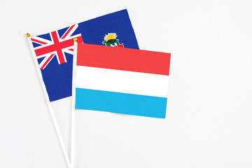 Luxembourg and Cayman Islands stick flags on white background. High quality fabric, miniature national flag. Peaceful global concept.White floor for copy space.