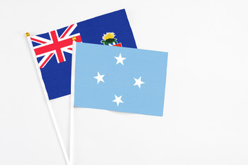 Micronesia and Cayman Islands stick flags on white background. High quality fabric, miniature national flag. Peaceful global concept.White floor for copy space.
