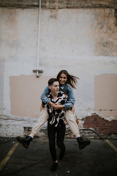 Young man giving beautiful woman a piggyback ride