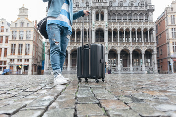 Woman tourist goes with a suitcase at the Grand Place in Brussels, Belgium