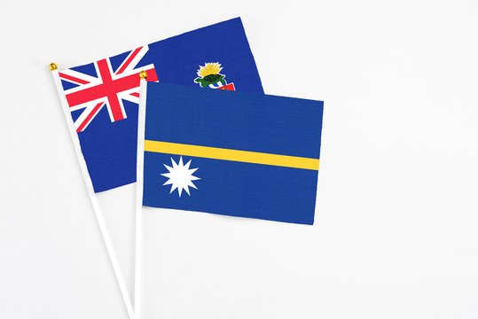 Nauru and Cayman Islands stick flags on white background. High quality fabric, miniature national flag. Peaceful global concept.White floor for copy space.