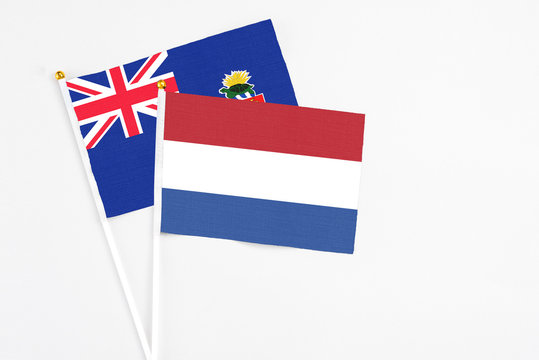 Netherlands and Cayman Islands stick flags on white background. High quality fabric, miniature national flag. Peaceful global concept.White floor for copy space.