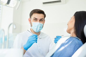 Fototapeta na wymiar portrait of male dentist looking at the camera in mask and holding instruments for looking client
