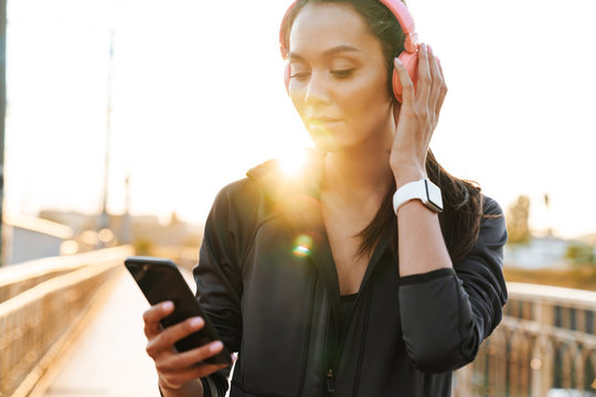 Image of attractive athletic woman using cellphone and headphones