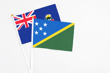 Solomon Islands and Cayman Islands stick flags on white background. High quality fabric, miniature national flag. Peaceful global concept.White floor for copy space.