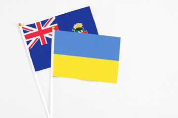 Ukraine and Cayman Islands stick flags on white background. High quality fabric, miniature national flag. Peaceful global concept.White floor for copy space.